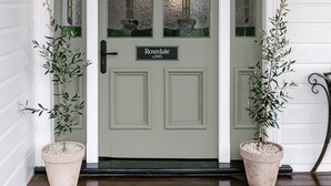 A front door with a sign reading "Rosedale c.1905", flanked by two potted plants and a black lantern. - Maleny Lodge (Maleny)