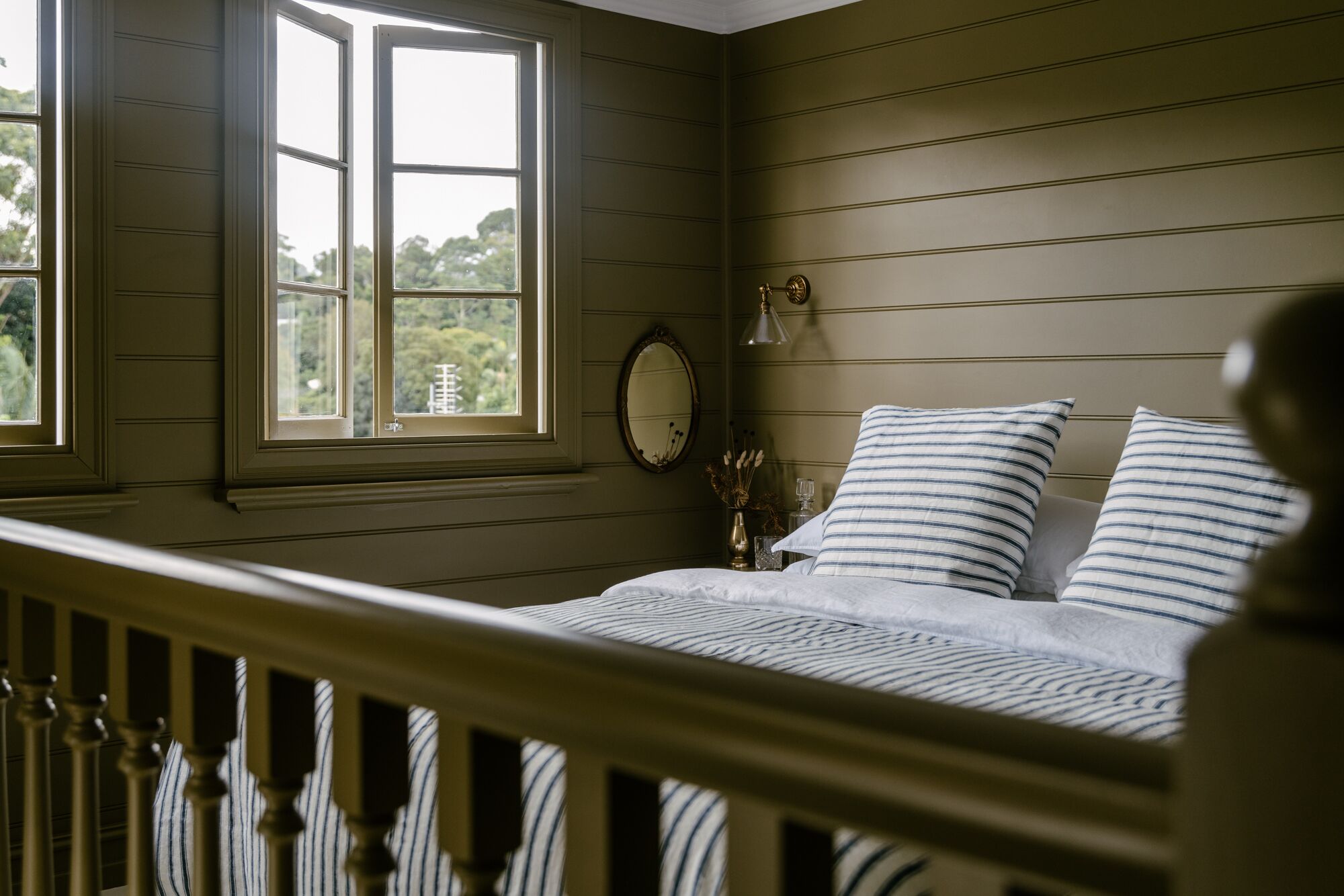 A bedroom with a bed, a window, a mirror, and a nightstand.