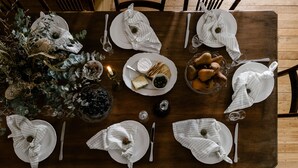 A wooden dining table set with plates, cutlery, and a centerpiece of greenery and decorative items. - Maleny Lodge (Maleny)