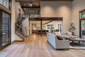 A spacious living area with a staircase, a sofa, a coffee table, and a view of the kitchen. - Family Friendly w/ Suncadia Pool Access (Cle Elum)