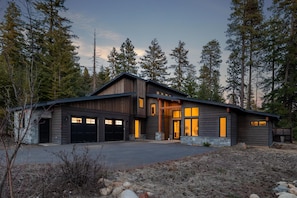 A modern two-story house with a garage, large windows, and a stone foundation.
