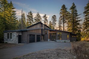 A modern two-story house with a stone facade, a garage, and a driveway.