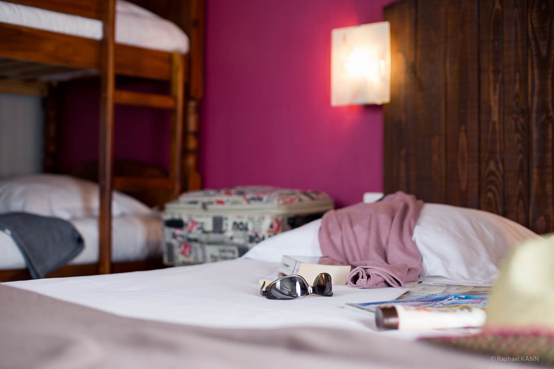 Une chambre avec des lits superposés, une table de chevet avec une lampe et un mur rose.