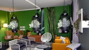 A modern living room with green walls, yellow sofa, white chairs, and hanging black lanterns. - Domaine de Garabaud (Mazeres)