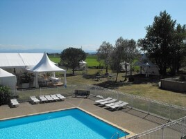 Una piscina con sillas de descanso y una estructura tipo carpa blanca.