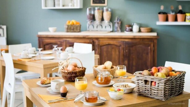 A breakfast setting with a wooden table, baskets of fruits, eggs, and a coffee station. - Domaine de Garabaud (Mazeres)