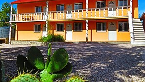 A two-story building with a red roof and yellow walls, featuring multiple windows and a balcony. - Cabañas Darely (Urique)