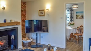 Una sala de estar acogedora con chimenea, un televisor de pantalla plana, una mesa de centro con revistas y un comedor con mesa y sillas.