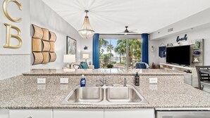 A modern kitchen with a granite countertop, double sink, and a ceiling fan.