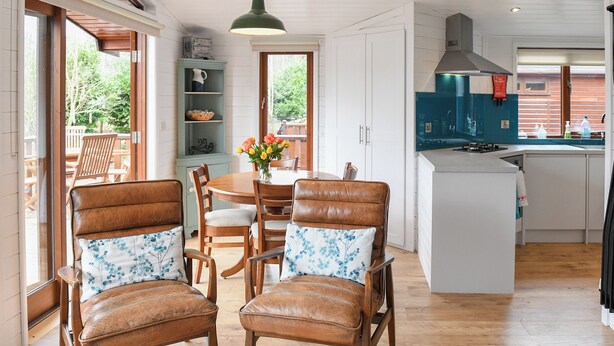 Una cocina moderna con comedor, con mobiliario de madera y vistas al exterior.