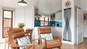 Un salón amplio con sillones de cuero, una mesa de comedor y una cocina visible a través de un acceso abierto.