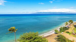 A beach with clear blue water, palm trees, and a view of a mountain range. - UPGRADED-Sands of Kahana #275 OCEANFRONT, 3 Bed Rooms, sleeps 10 - Central AC (Lahaina)