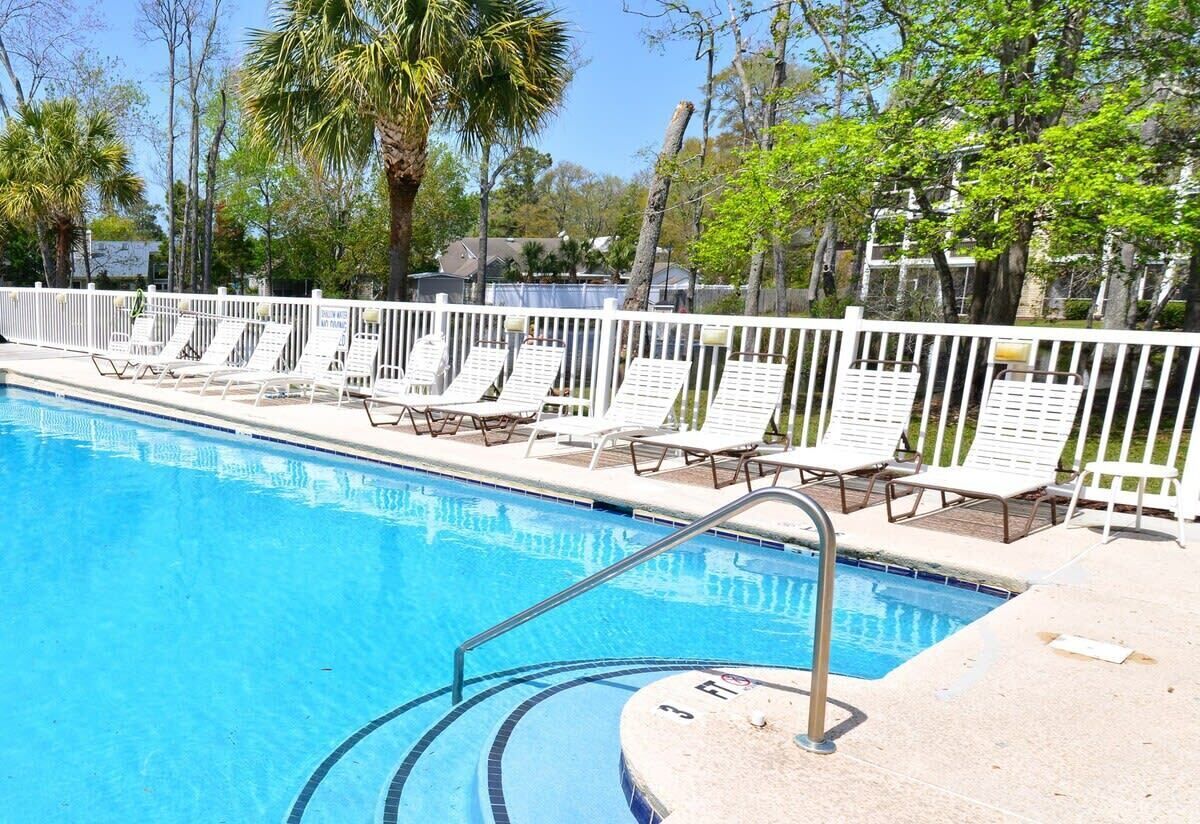 Une piscine avec des chaises longues et une clôture blanche.