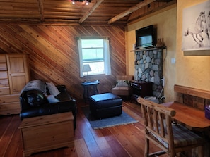 L’intérieur d’un chalet confortable, avec une cheminée, un téléviseur et un mur en pierre.