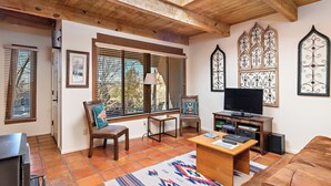 Una sala de estar con techo de madera, televisor, mesa de centro y chimenea.