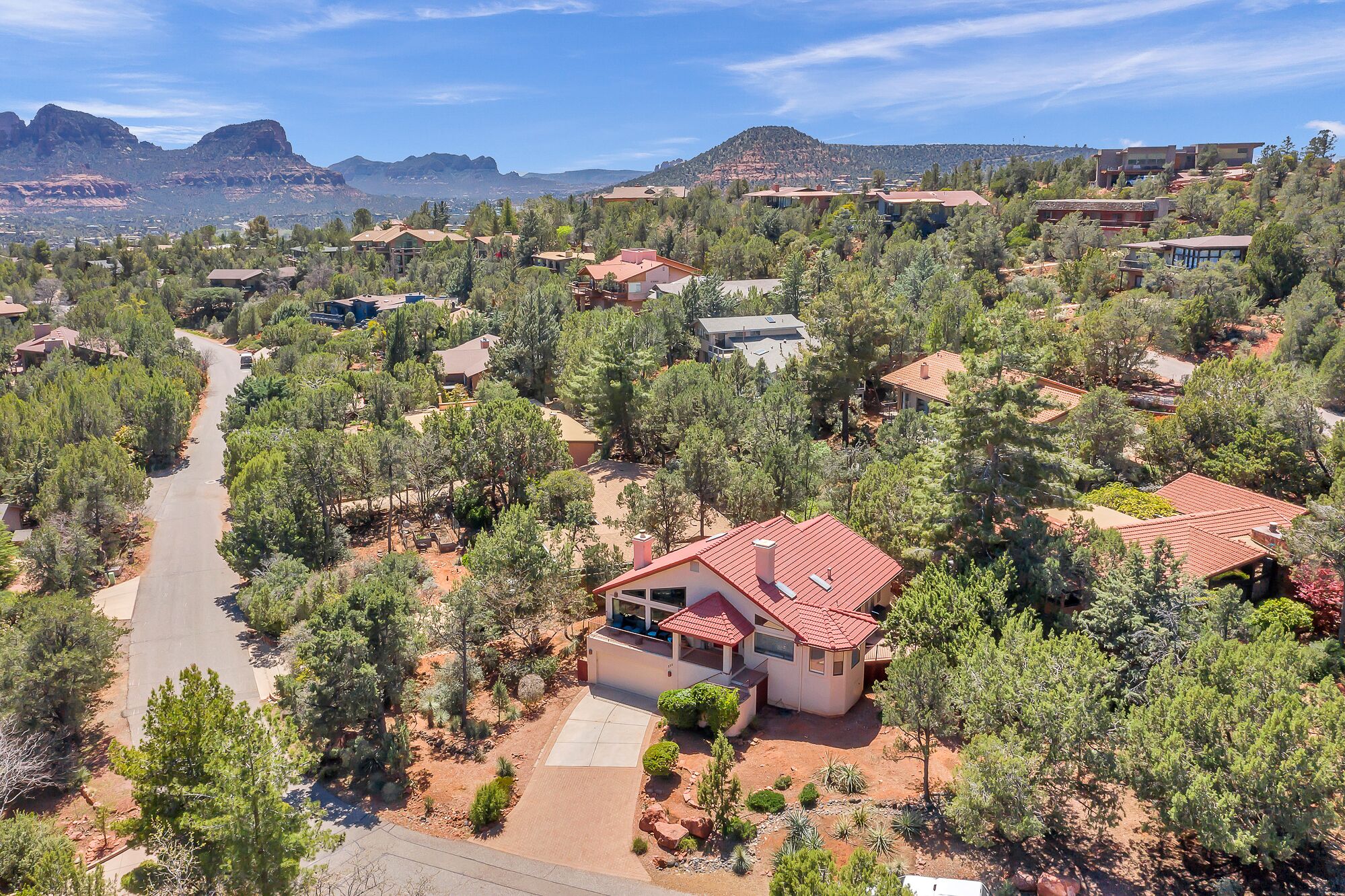Un barrio residencial con casas rodeadas de árboles y una vista despejada de montañas al fondo.
