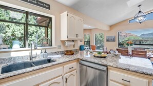 Cucina con un'ampia finestra, lavastoviglie e zona pranzo con tavolo e sedie.