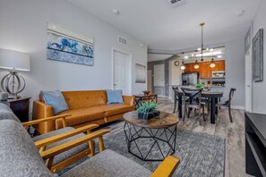 A modern living room with a sofa, coffee table, and dining area.