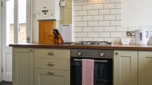 Een keuken met een ingebouwde oven, een gasfornuis, een houten aanrechtblad en een hangende keukendoek.