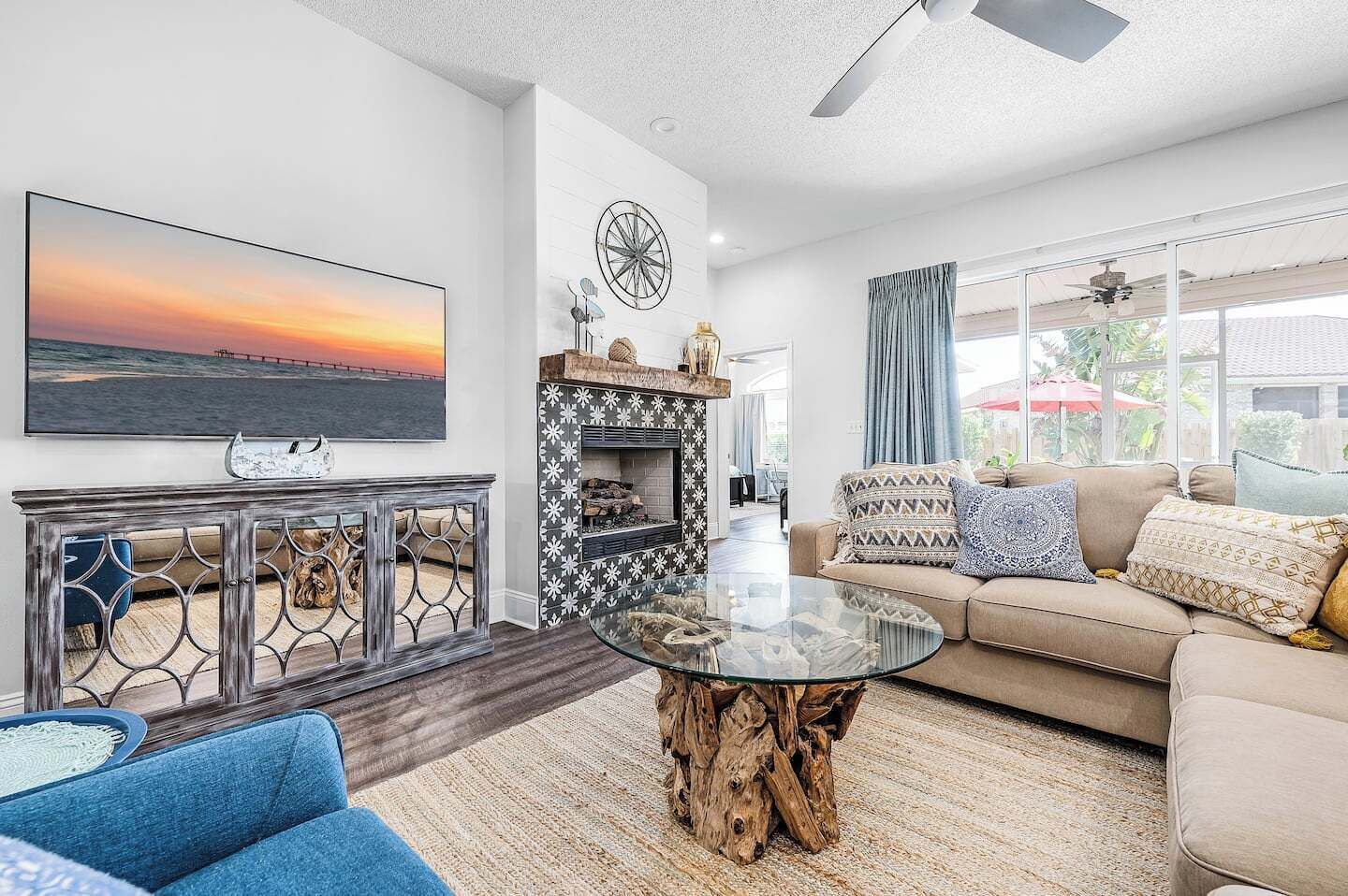 A modern living room with a large TV, a fireplace, and a glass coffee table.
