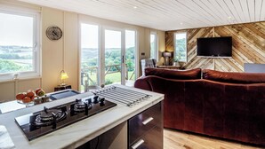 Una cucina moderna con piano cottura a gas, un'area pranzo con divano rosso e un'ampia finestra con vista panoramica.