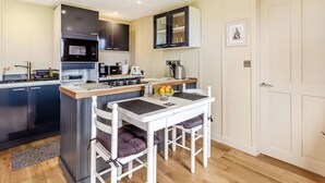 Una cucina compatta con un'isola centrale, un forno a microonde, un bollitore e un lavandino.