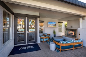 A hotel entrance with a glass door, outdoor seating area, and a fireplace. - King Bed / Prime Location / Private Garage (Roseville)