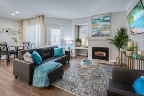 A living room with a fireplace, a dining area, and a large painting on the wall. - King Bed / Prime Location / Private Garage (Roseville)