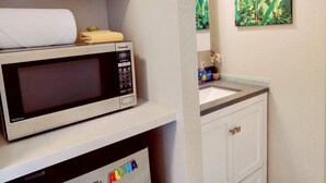 Eine kleine Küche mit einer Mikrowelle auf einem Regal, einem Spülbecken und einem Schrank.