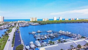 Un puerto deportivo con numerosas embarcaciones amarradas, una carretera aledaña y edificios al fondo.
