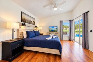 A bedroom with a bed, bedside tables, a ceiling fan, a painting, and a view of a pool through a sliding door. - 4BR Pool Home 15 min to Disney • Heated Pool & Spa • Game Room (Kissimmee)