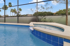 A swimming pool with a curved edge, surrounded by a fence and palm trees. - 4BR Pool Home 15 min to Disney • Heated Pool & Spa • Game Room (Kissimmee)
