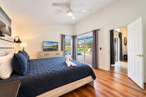 A bedroom with a large bed, a flat-screen TV, a ceiling fan, and a view of a swimming pool through glass doors. - 4BR Pool Home 15 min to Disney • Heated Pool & Spa • Game Room (Kissimmee)
