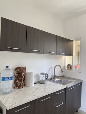 Enjoy cooking in this well-equipped kitchen with a stainless steel sink, modern faucet, and large water dispenser.