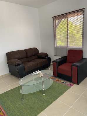 Relax in this stylish living room with a sofa, armchair, and glass coffee table.