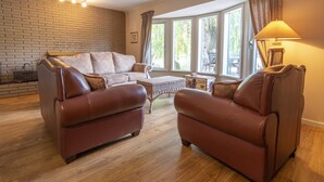 Una sala de estar con un sofá de cuero marrón, una mesa de centro de madera y una lámpara.