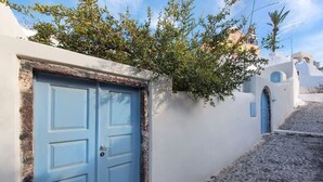 A narrow street with a blue door and white walls, typical of a Mediterranean village. - Nykteri Cave | A Terre Cave Villas (Oia)