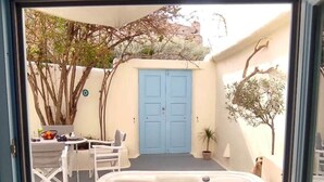 A hot tub with a view of a blue door and a patio area with outdoor furniture. - Nykteri Cave | A Terre Cave Villas (Oia)