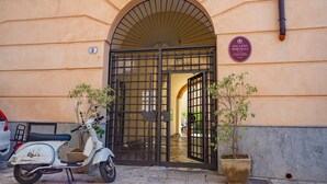 A gated entrance with a sign for Palazzo Porcelli, a parked scooter, and potted plants. - Dante's house, in the historic center of Palermo (Palermo)