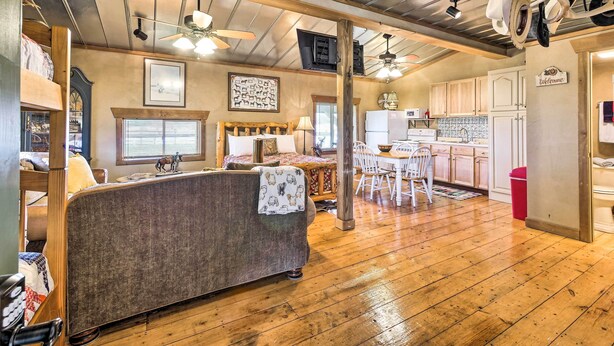 A cozy living room with a sofa, wooden ceiling, and a dining area with a table and chairs. - Renovated Bunkhouse on 12-Acre Horse Farm! (Perrysville)