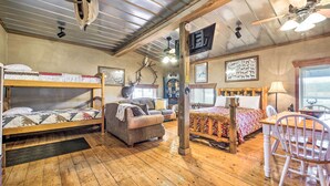 A rustic cabin-style room with bunk beds, a sofa, a dining table, and a ceiling fan. - Renovated Bunkhouse on 12-Acre Horse Farm! (Perrysville)