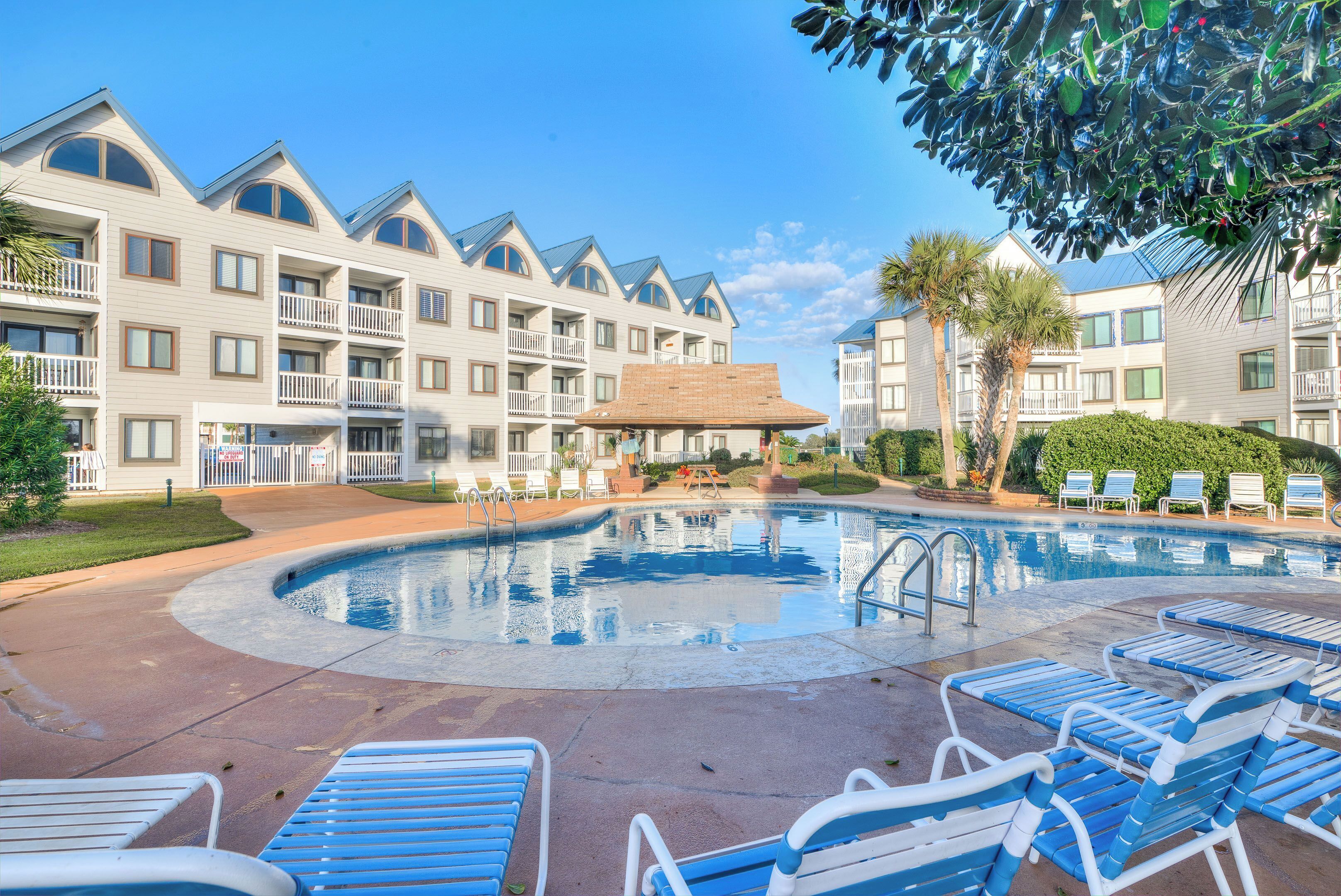A hotel with a swimming pool, lounge chairs, and a well-maintained garden.