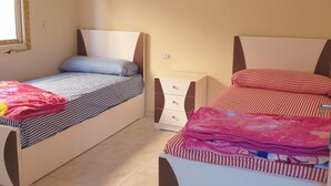 Ein Schlafzimmer mit zwei Betten, einem Nachttisch und einem Fenster.
