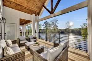 A covered outdoor seating area with wicker furniture and a view of a lake. - ~Luxury Home~Gorgeous Lake View~Sleeps 14~Private Dock~ (Crane Hill)