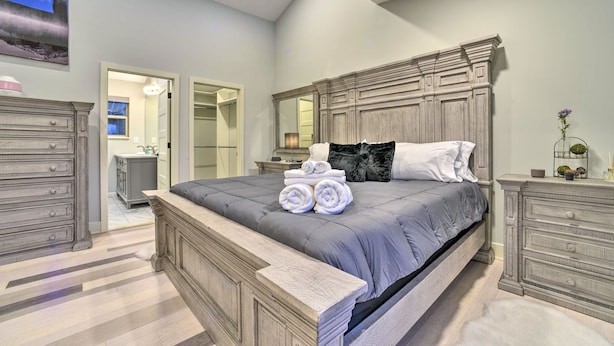 Et soveværelse med en stor seng, træsenggavl og et walk-in closet.