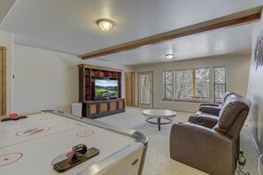 Uma sala de lazer com mesa de bilhar, televisão e um espaço de estar confortável.
