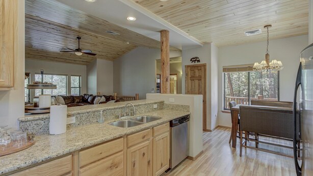 A spacious kitchen with granite countertops, wooden cabinets, and a built-in dishwasher. - Bison Ridge 4 BR, 4BA Cabin with National Forest access and views! (Show Low)