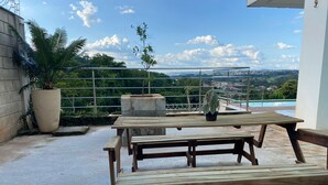 A wooden picnic table with benches on a rooftop terrace overlooking a cityscape. - Two-story house with pool, well located, 5 minutes from Flamboyant Shopping Center. (Goiânia)