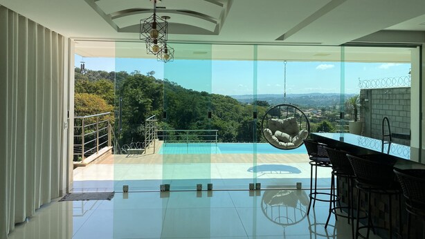 A modern interior with a glass wall, a hanging chair, and a bar area. - Two-story house with pool, well located, 5 minutes from Flamboyant Shopping Center. (Goiânia)
