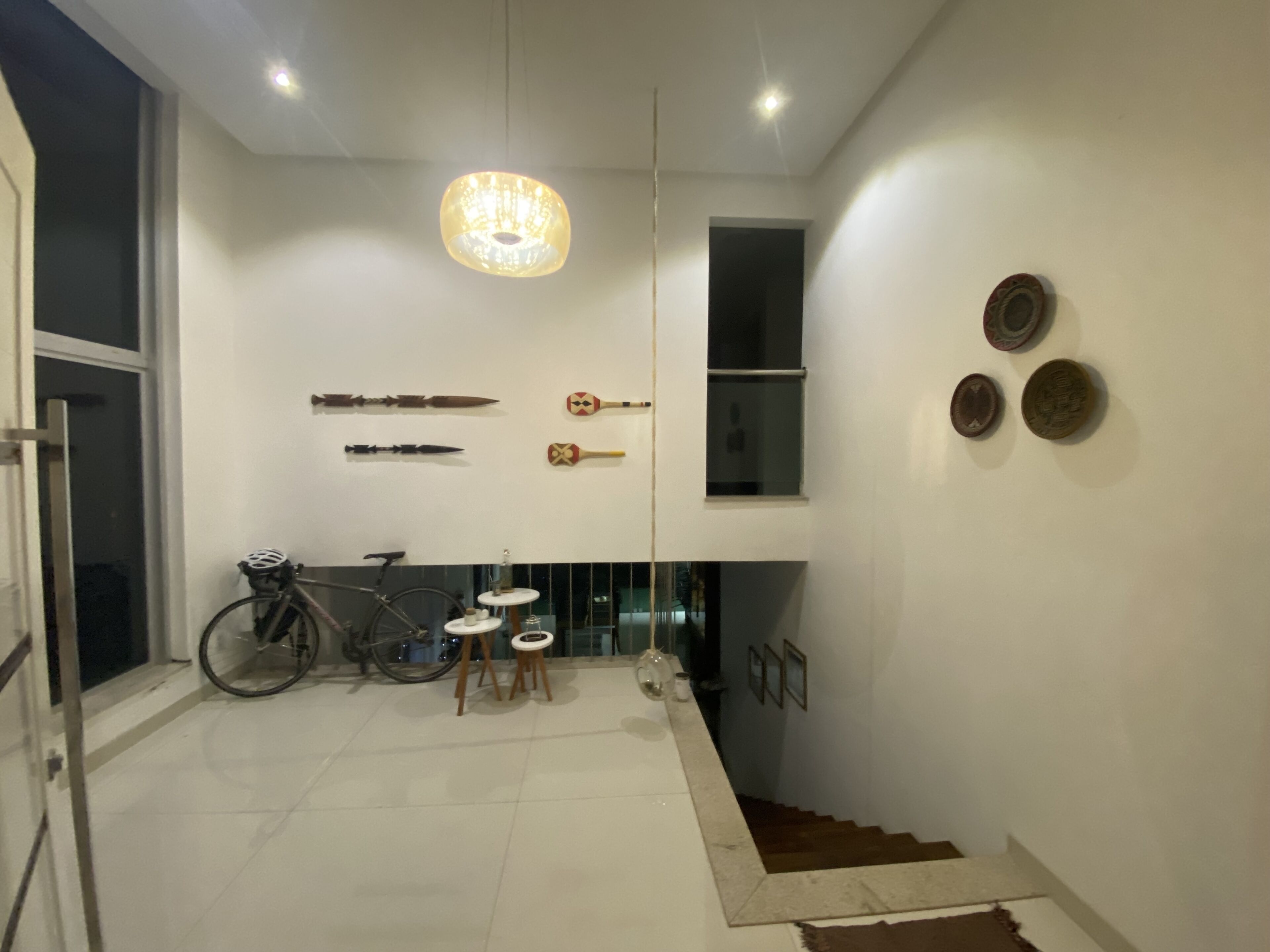 A modern interior with a staircase, a bicycle, and wall-mounted artifacts.